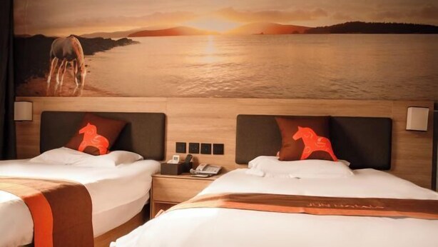 A hotel room with two beds, a mural of a sunset over water, and horse-shaped pillows. - Junyi Chain Hotel (Haiyan Qiyuan Chengbei East Road) (Haiyan)