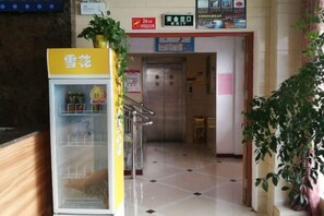 A reception area with a vending machine, a staircase, and a door leading to an elevator. - Junyi Chain Hotel (Haiyan Qiyuan Chengbei East Road) (Haiyan)