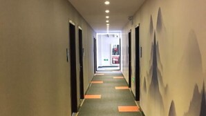 A hotel corridor with a carpeted floor, doors on both sides, and a wall with a mountain design. - Junyi Chain Hotel (Haiyan Qiyuan Chengbei East Road) (Haiyan)