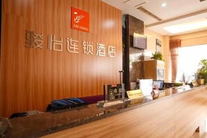 A hotel reception desk with a wooden panel wall, a reception counter, and a sign indicating the hotel name. - Junyi Chain Hotel (Haiyan Qiyuan Chengbei East Road) (Haiyan)