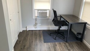 Un pequeño espacio de oficina con un escritorio, una silla y una ventana con persianas.