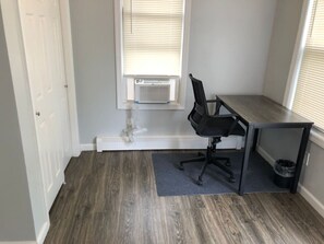 A small office space with a desk, chair, and a window with blinds.