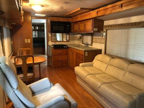 Interior compacto de una caravana con cocina americana, comedor y zona de estar.