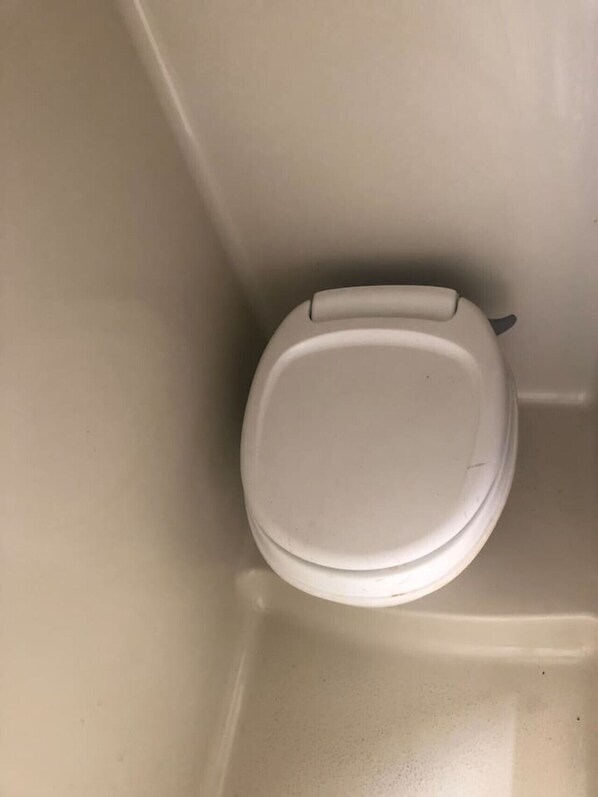 A white toilet in a bathroom with a plain wall and no visible amenities or features. - Cozy RV, direct bus to NYC 2 blocks away, MetLife Stadium 30 minutes (Linden)