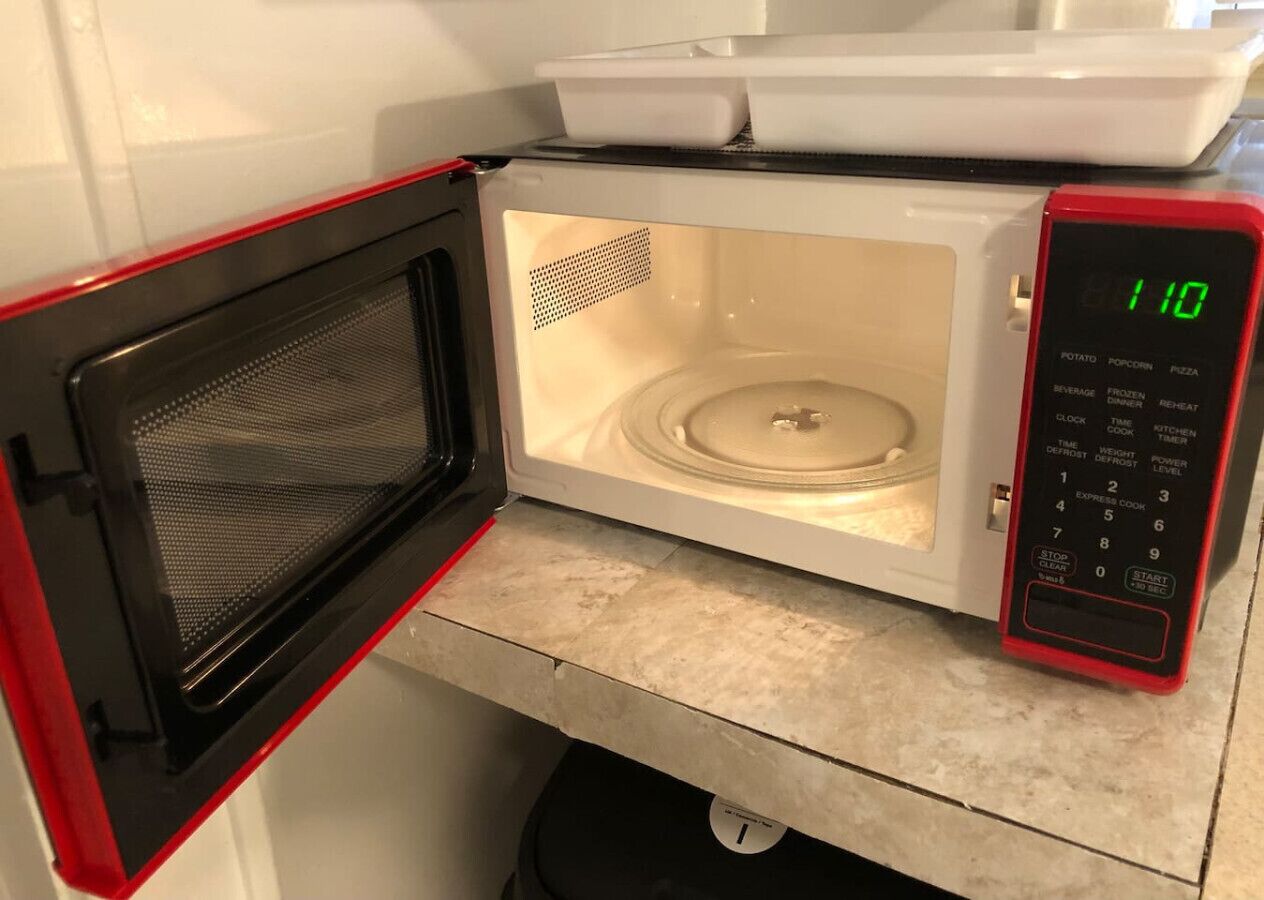 An open microwave with a digital display showing 110.
