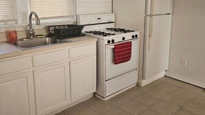 A compact kitchen with white cabinetry, a gas stove, a built-in oven, and a white refrigerator.