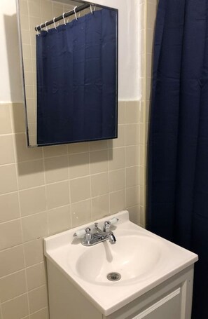 A bathroom with a white sink, a mirror, and a blue shower curtain.