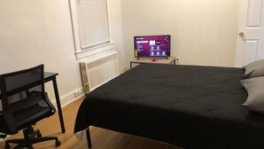 A bedroom with a bed, a desk, and a computer monitor.