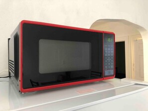 Un four à micro-ondes avec un cadre rouge et un écran numérique situé sur le côté droit.