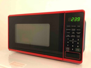 Un four à micro-ondes rouge doté d’un écran numérique affichant l’heure : 8 h 23 min 39.