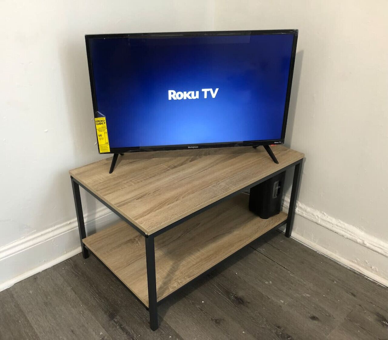Un téléviseur posé sur un meuble en bois, avec une étagère en dessous.