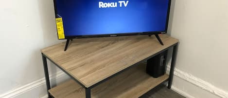 A TV on a wooden stand with a shelf underneath.