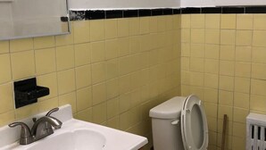 A bathroom with a white sink, wooden vanity, and a toilet.