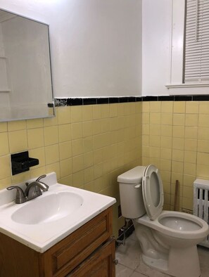 A bathroom with a white sink, wooden vanity, and a toilet.