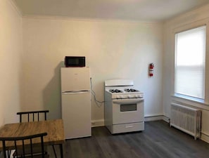 Une petite cuisine équipée d’un réfrigérateur, d’une cuisinière et d’une table à manger avec deux chaises.