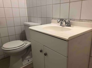 Une salle de bain avec des toilettes, un lavabo et un meuble de rangement.