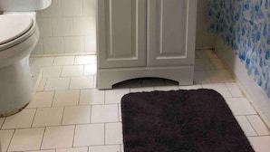 A bathroom with a toilet, a sink with a mirror, and a shower curtain.
