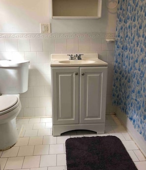 Une salle de bain avec des toilettes, un lavabo avec un miroir et un rideau de douche.