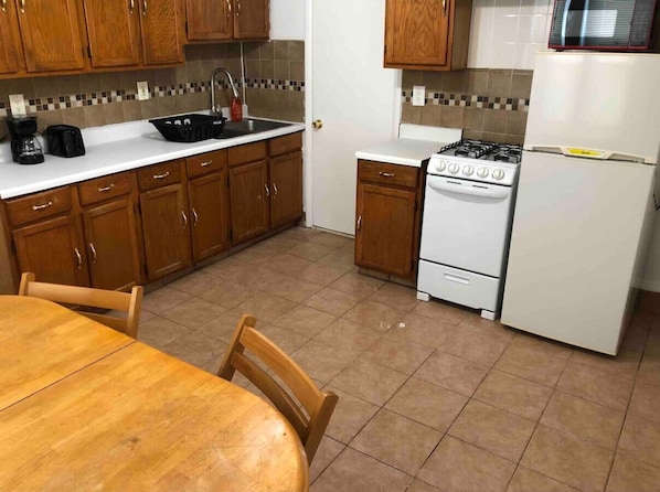 A kitchen with wooden cabinets, a white countertop, a stove, a sink, and a refrigerator.