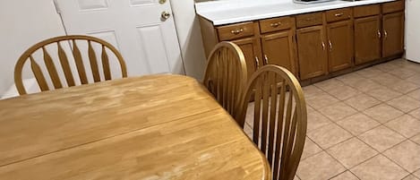 Una cocina con armarios de madera, encimera blanca y suelo de baldosas.