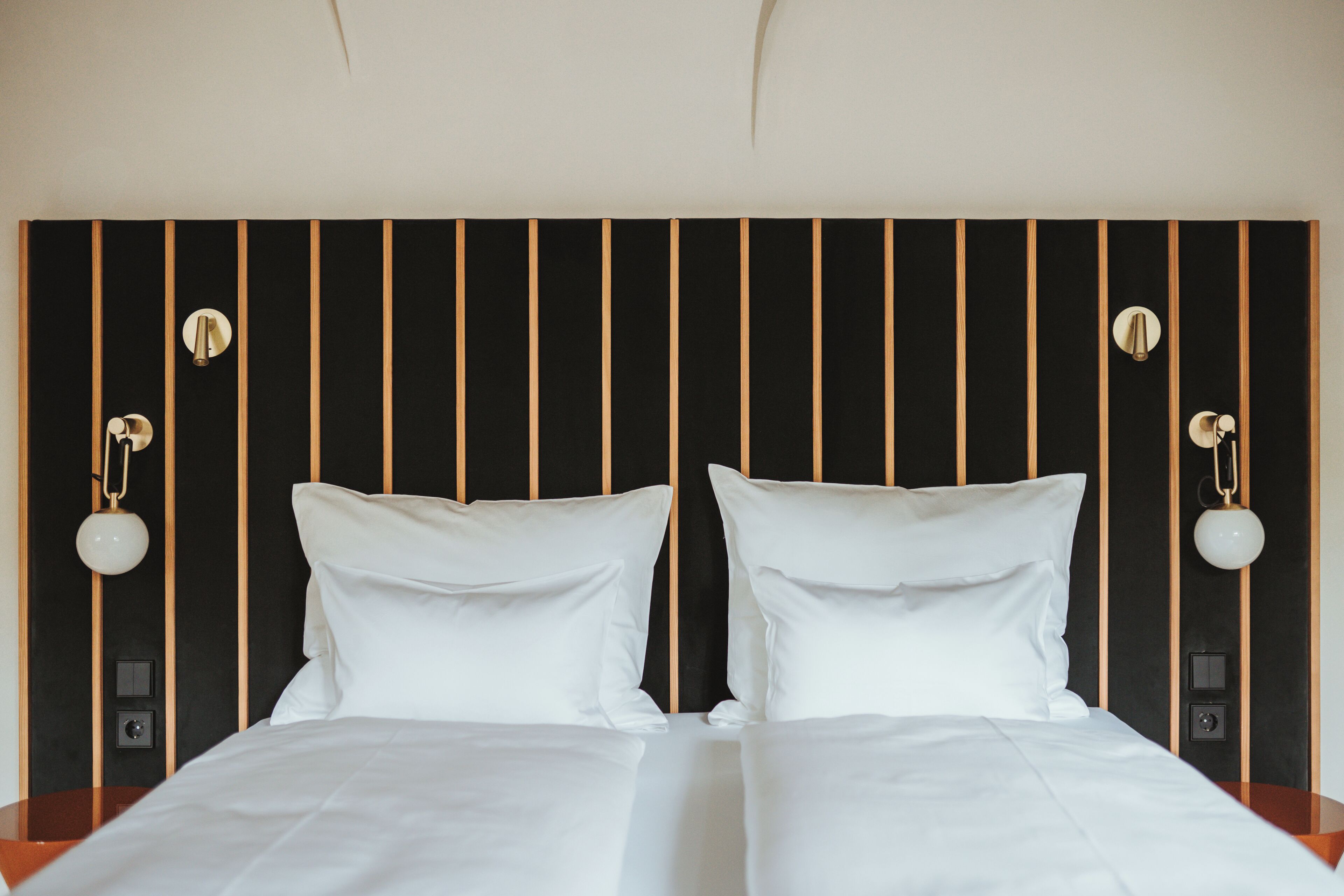 A double bed with white linens, a black and gold headboard, and two bedside lamps.
