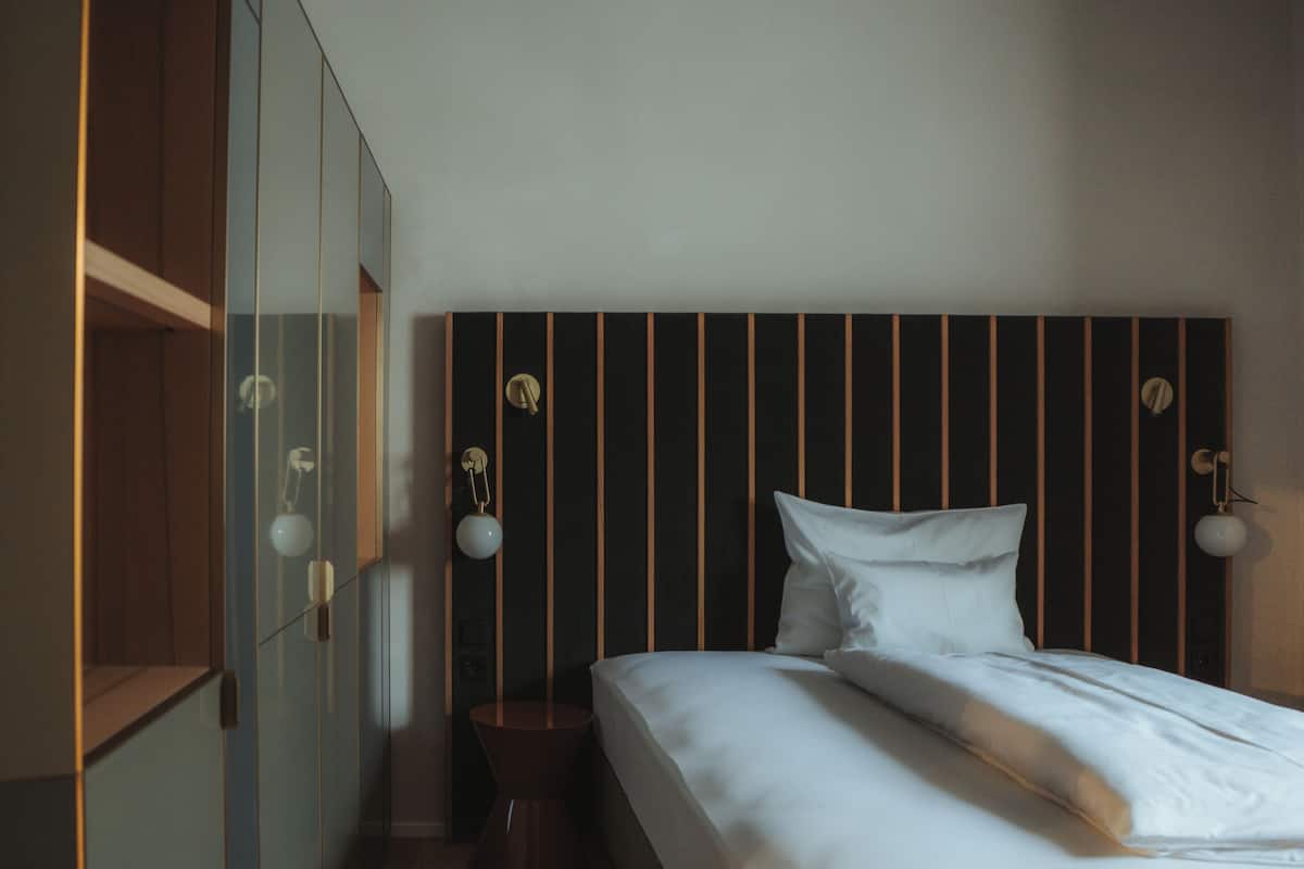 Ein Schlafzimmer mit Bett, Nachttischlampen, einem Holzschrank und einem Nachtkästchen.