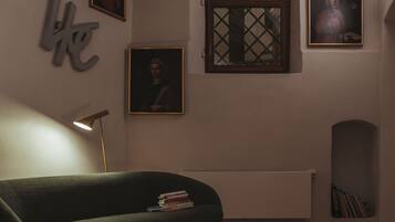 Ein Zimmer mit einem grünen Sofa, einem Heizkörper und gerahmten Bildern an der Wand.