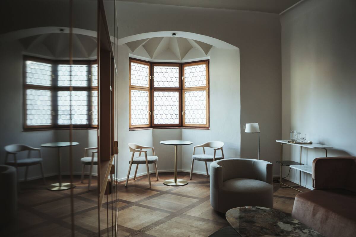 Ein modernes Zimmer mit einem großen Erkerfenster, einem runden Tisch und mehreren Stühlen.