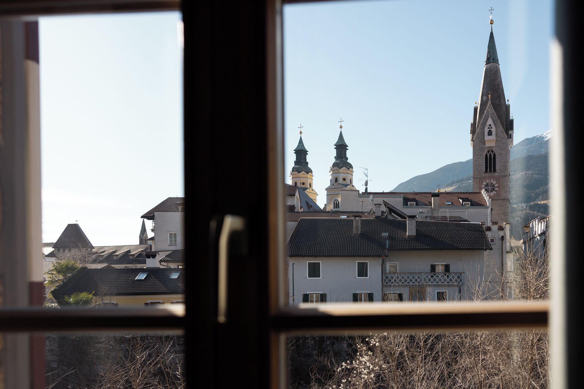 Vista a través de una ventana de un edificio con una iglesia que cuenta con dos torres y un campanario.