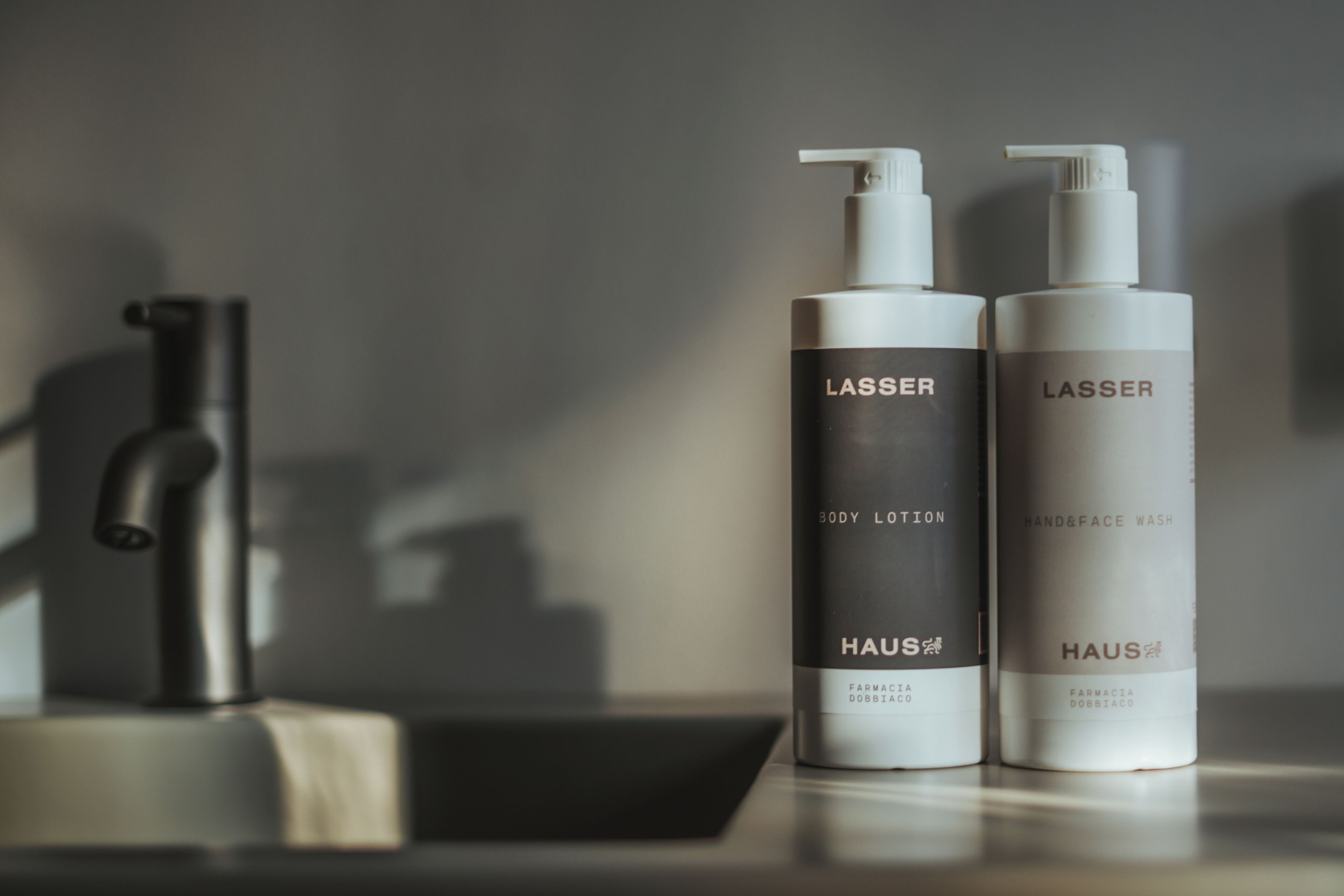 Deux flacons de lotion corporelle LASSER et un produit pour laver les mains et le visage sont posés sur un comptoir.