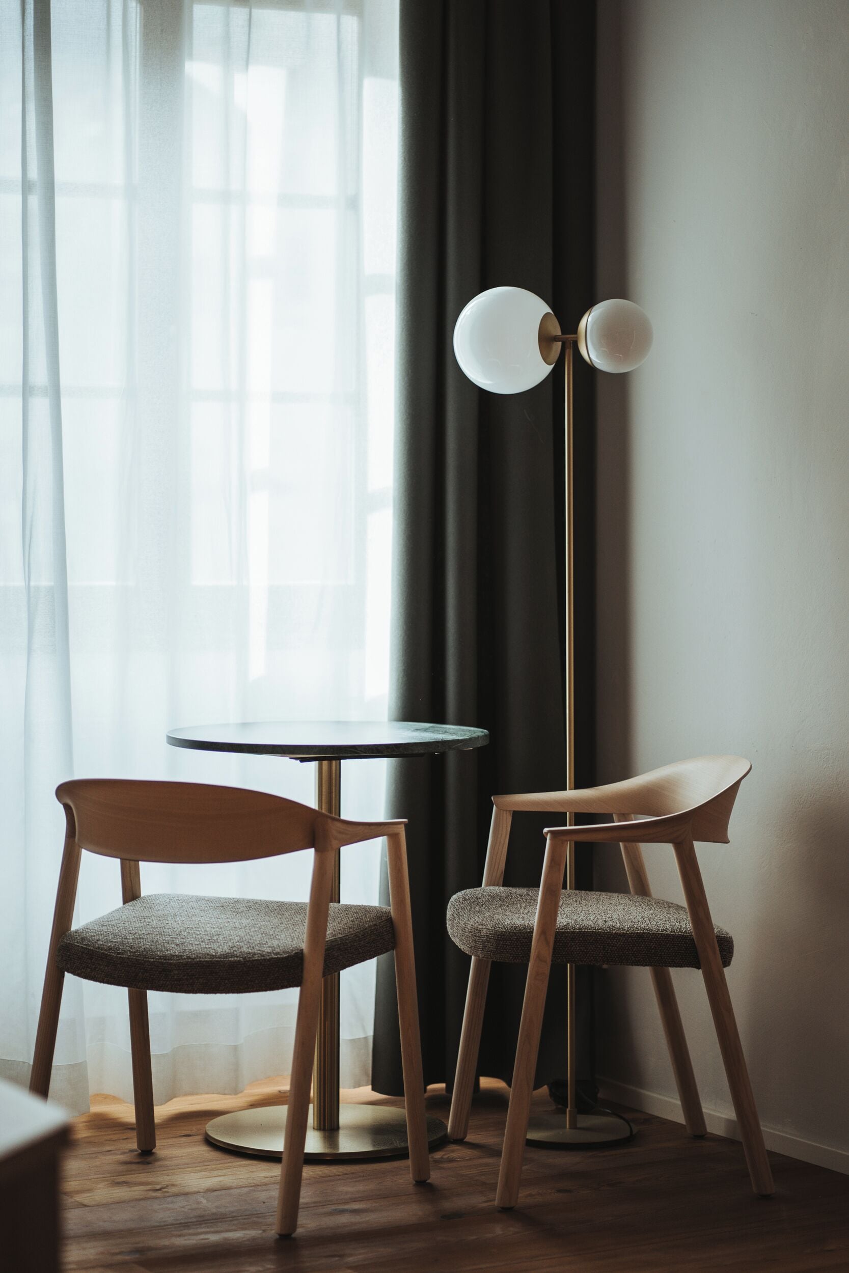 A room with two chairs, a round table, and a floor lamp.