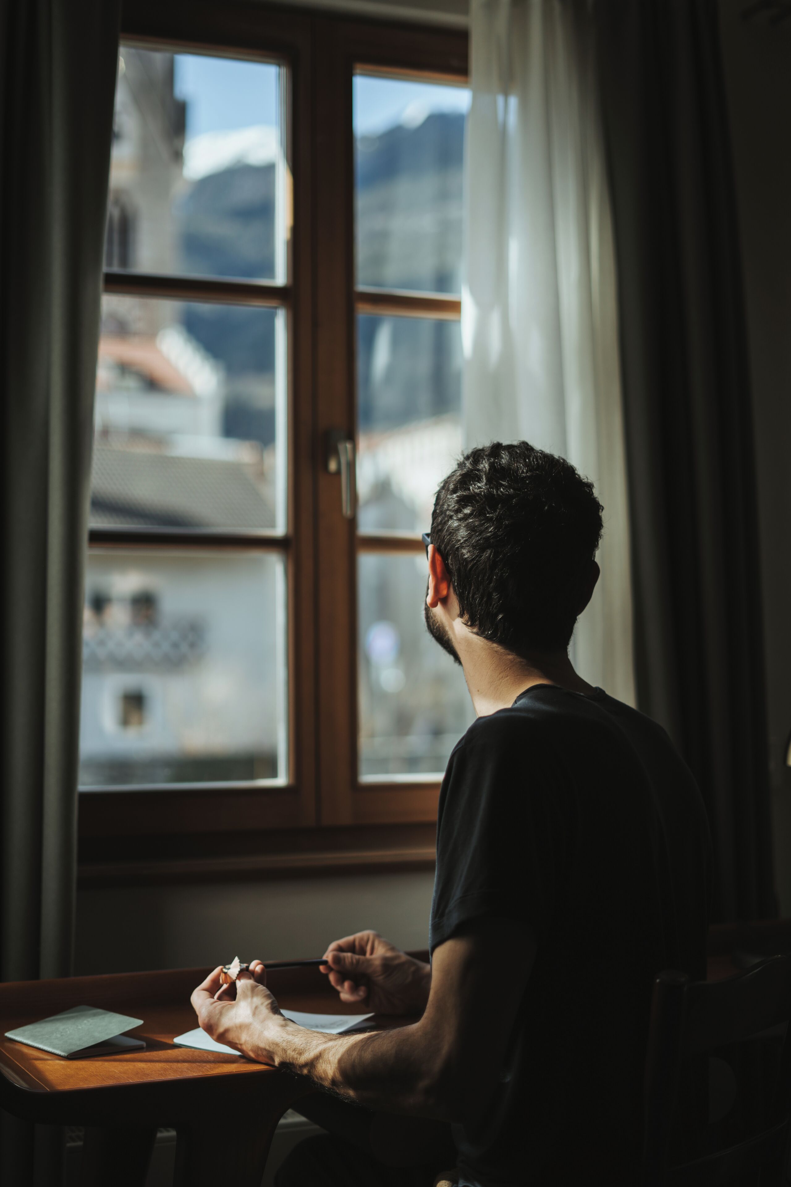 A person sitting at a wooden desk with a window in the background.