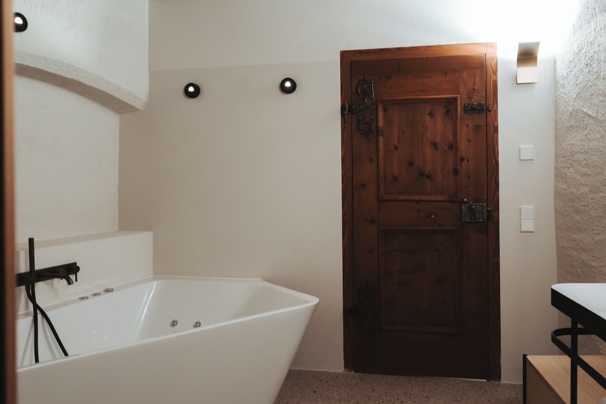 Ein Badezimmer mit einer weißen Badewanne, einer Holztür und einem weißen Waschbecken.