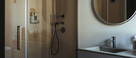 A modern bathroom with a glass-enclosed shower, a round mirror, and a wooden vanity.