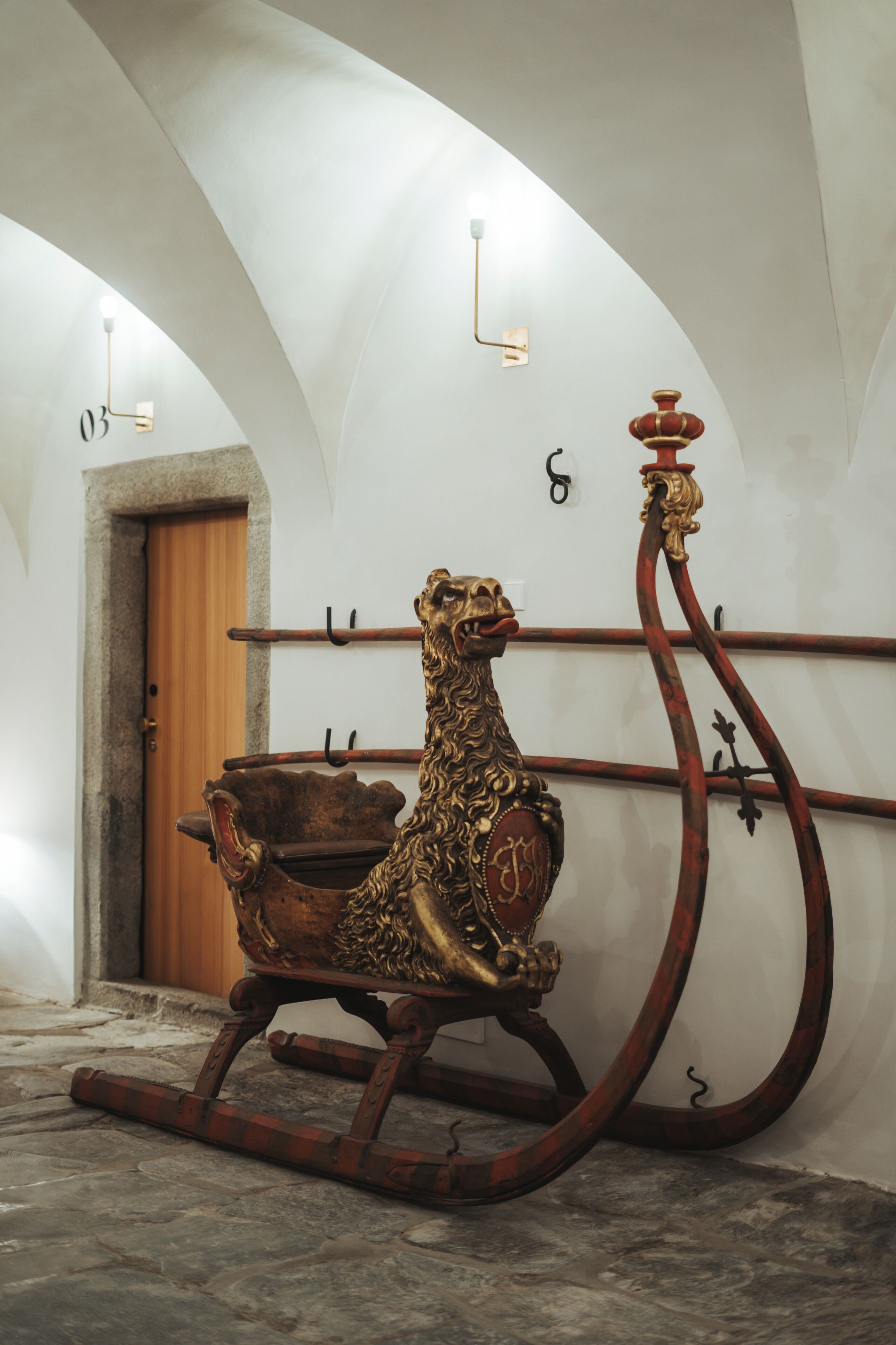 Une pièce dotée d’une porte en bois, d’une statue de lion décorative posée sur une luge et d’un plafond voûté.