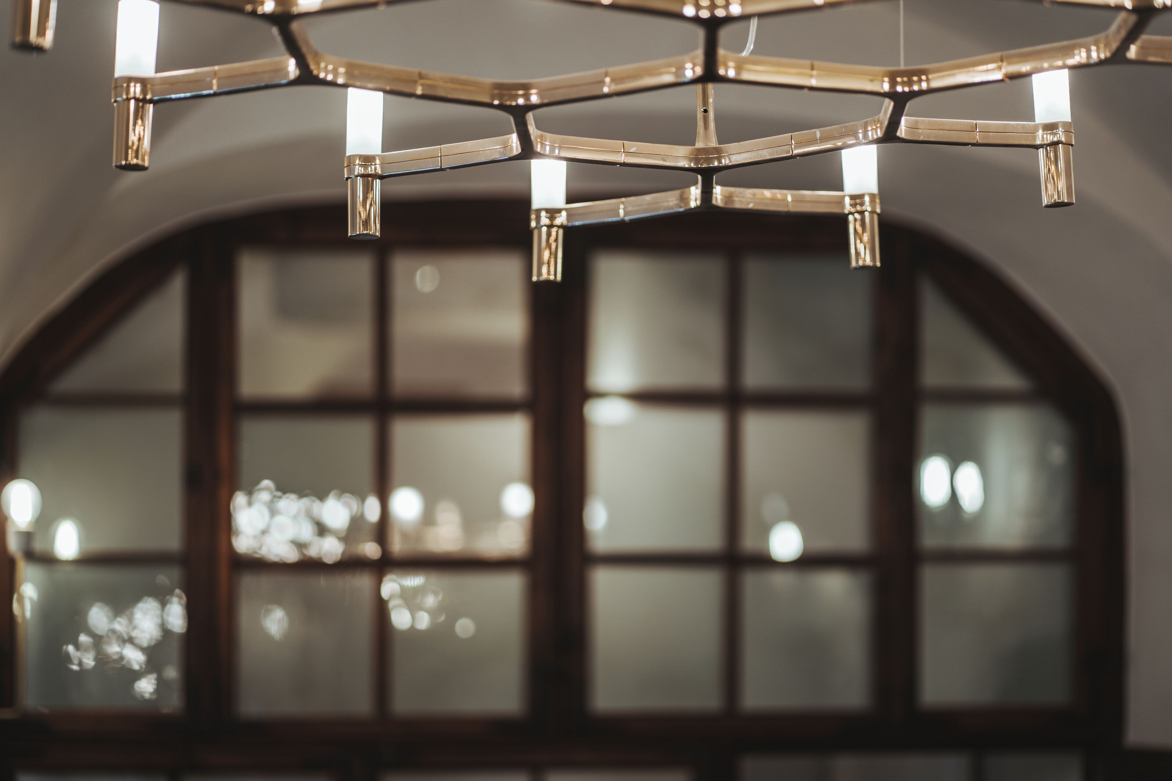 Un candelabro con múltiples lámparas colgando de una estructura metálica geométrica.