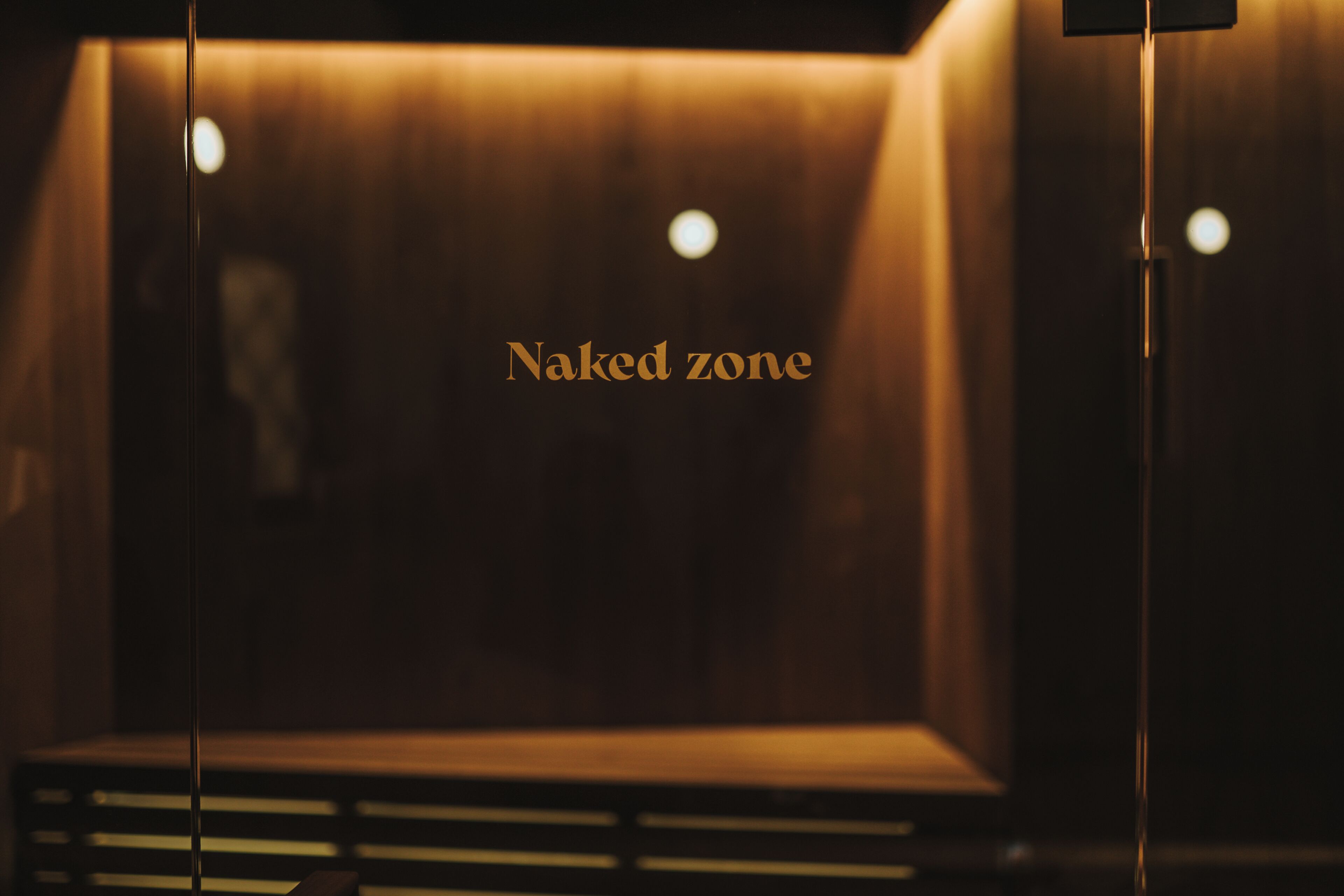 A room with a wooden wall and a sign reading "Naked zone".