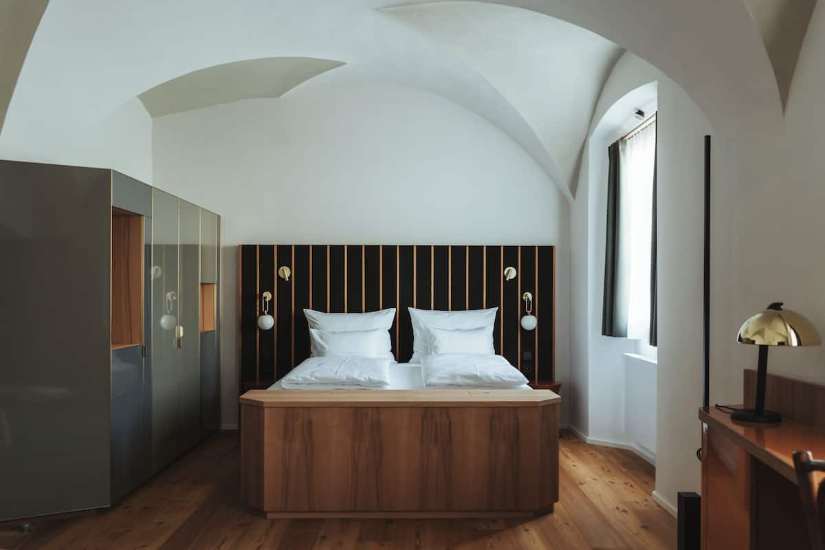 Ein Schlafzimmer mit einem hölzernen Bett, einem Kleiderschrank und einem Schreibtisch mit einer Lampe.