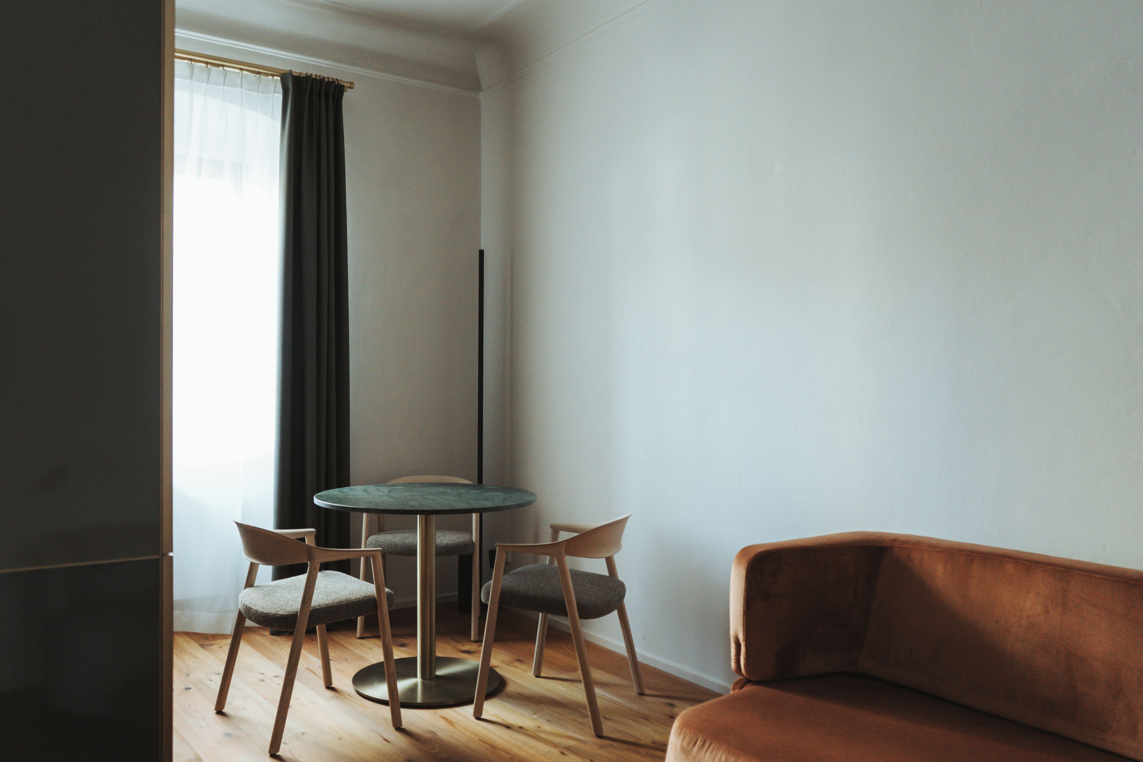 Une pièce comprenant une table ronde, deux chaises, un canapé et un grand lampadaire.