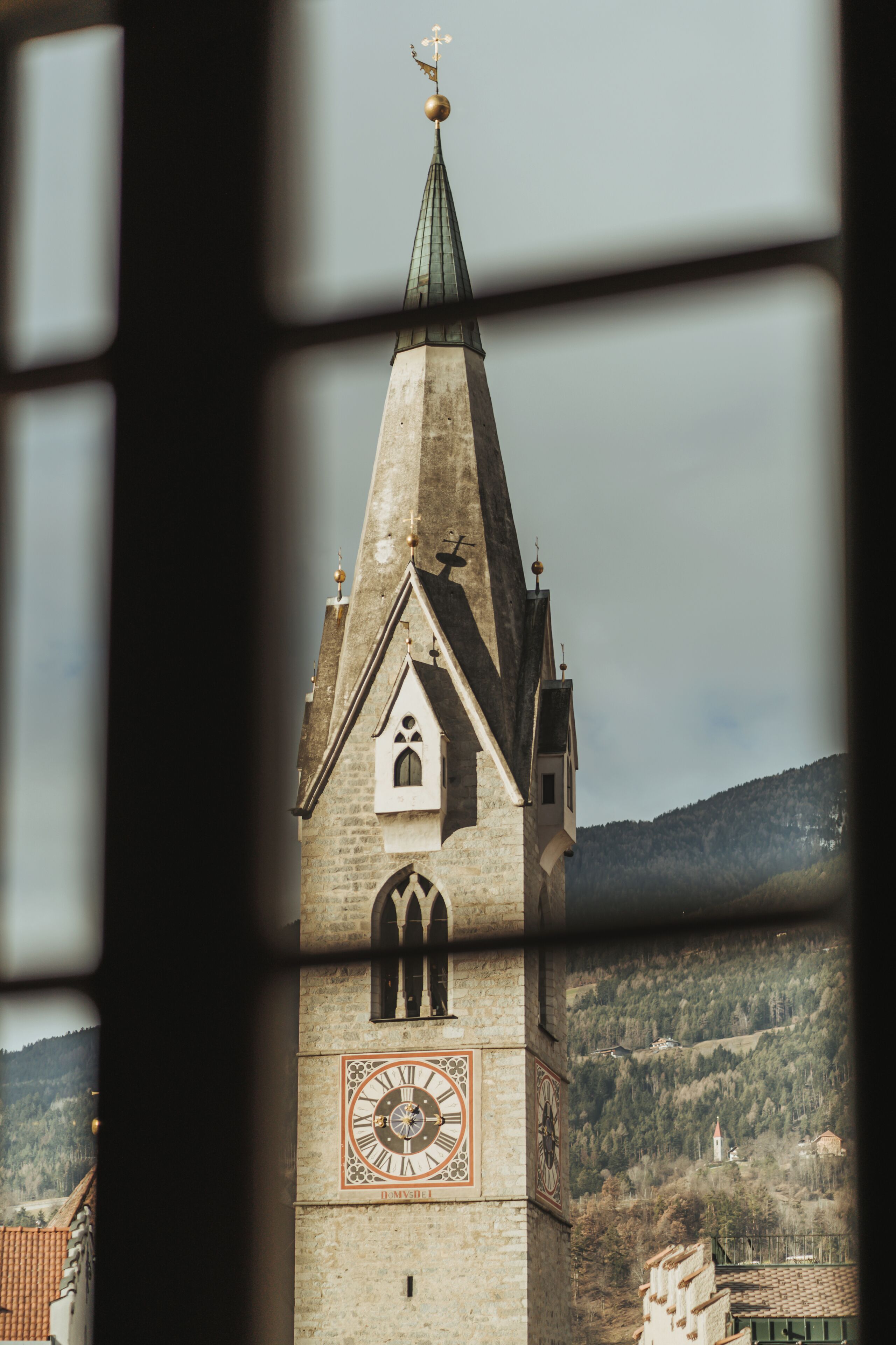 Una torre histórica con un reloj, un techo puntiagudo y una veleta.