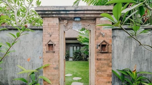 Una entrada de ladrillo con un pequeño jardín y piedras para caminar.