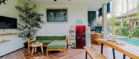 A living room with a green sofa, wooden table, and a ceiling fan.