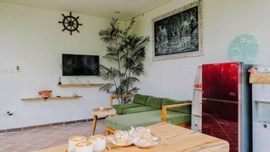 A living room with a wooden table, green sofa, and a red refrigerator. - The Kumpi Bali by the Lavana (Bali)