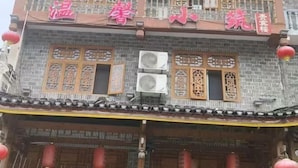 A traditional building with multiple windows, some with decorative wooden frames. There are air conditioning units installed on the exterior walls. - Wenxin Homestay (Zhangjiajie)