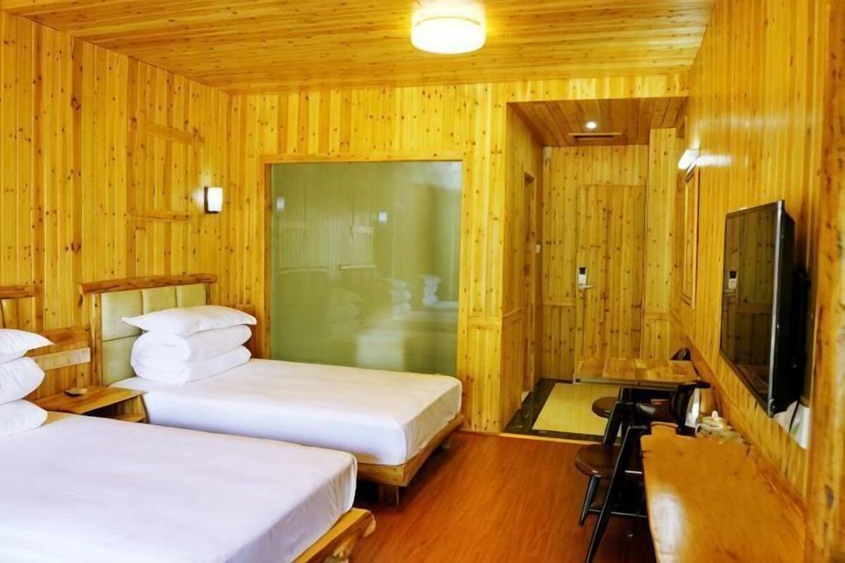 Une pièce en bois avec deux lits, une télévision et un espace douche.
