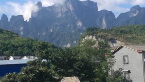 A mountainous landscape with a building featuring a sloped roof and a window. - Wenxin Homestay (Zhangjiajie)