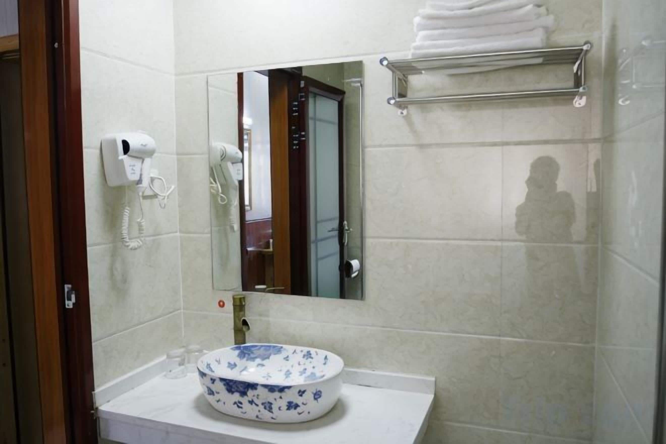 A bathroom with a sink, mirror, towel rack, and a hairdryer on the wall.