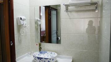 A bathroom with a sink, mirror, towel rack, and a hairdryer on the wall.