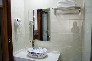 A bathroom with a sink, mirror, towel rack, and a hairdryer on the wall. - Wenxin Homestay (Zhangjiajie)