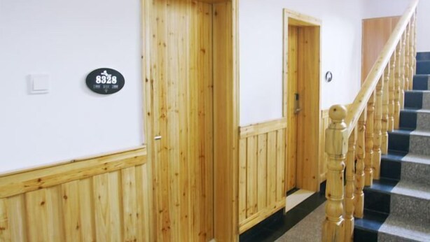 A hallway with wooden doors, a staircase with wooden balusters, and a black and white checkered floor. - Wenxin Homestay (Zhangjiajie)